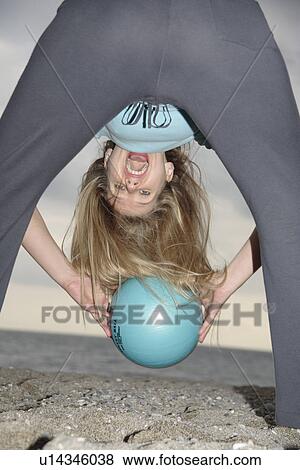 Young woman at the beach, tossing a ball through straddled legs View Large Photo Image Stock Photo - Young woman at the beach, tossing a ball through straddled legs. Fotosearch