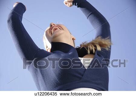 Young woman jumping happily in front of blue sky, view from below View Large Photo Image Stock Photography - Young woman jumping happily in front of blue sky, view from below. Fotosearch