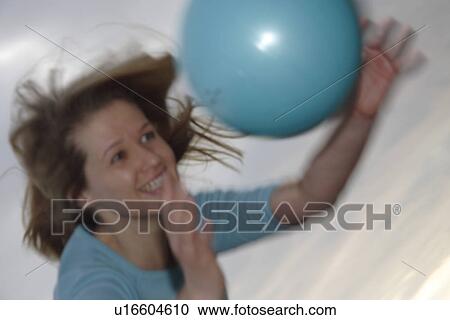 Stock Image - Young woman playing with a ball at the beach. Fotosearch