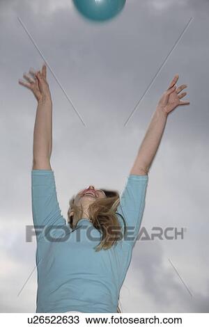 Stock Image - Young woman playing with a ball at the beach. Fotosearch