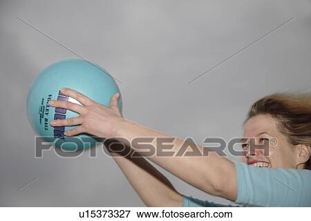 Stock Photo - Young woman playing with a ball at the beach. Fotosearch