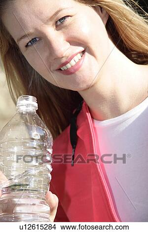 Picture - Female jogger holding water bottle, portrait. Fotosearch