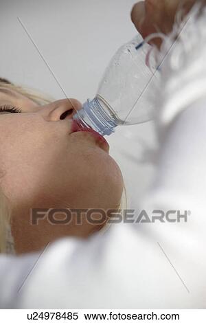 Stock Photography - Woman drinking water from plastic bottle, low angle view, close up. Fotosearch