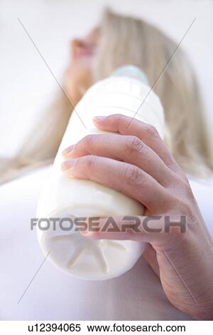Young blond woman holding milk bottle, view from below View Large Photo Image Stock Photography - Young blond woman holding milk bottle, view from below. Fotosearch