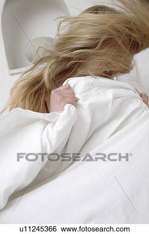 Young blond woman sitting up in bed and tossing her long hair View Large Photo Image Stock Photograph - Young blond woman sitting up in bed and tossing her long hair. Fotosearch