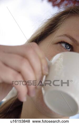 Stock Photo - Young woman drinking cup of coffe, close up. Fotosearch
