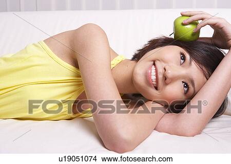 Picture - Portrait of Natural Young girl holding Apple, Smiling. Fotosearch