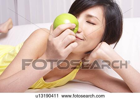 Stock Image - Portrait of Natural Young girl holding Apple, Smiling. Fotosearch