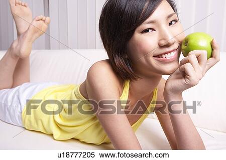 Stock Photography - Portrait of Natural Young girl holding Apple, Smiling. Fotosearch