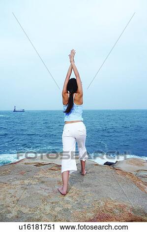 Young woman doing sun salutation, facing the sea View Large Photo Image Stock Image - Young woman doing sun salutation, facing the sea. Fotosearch