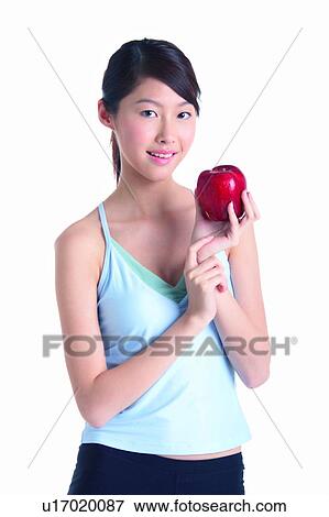 Stock Photo - Young woman holding red apple, front view. Fotosearch