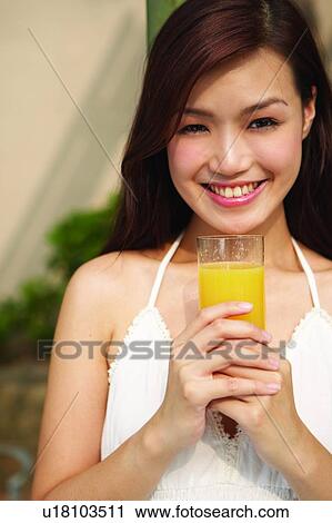 Young woman standing, holding glass of orange juice View Large Photo Image Stock Image - Young woman standing, holding glass of orange juice. Fotosearch