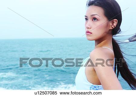 Young woman standing near the sea, looking Away View Large Photo Image Stock Photography - Young woman standing near the sea, looking Away. Fotosearch
