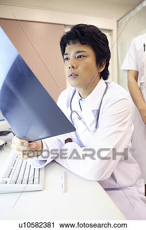 Doctor looking at X-ray View Large Photo Image Stock Image - Doctor looking at X-ray. Fotosearch