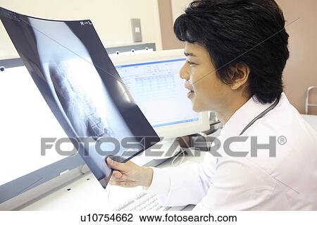 Doctor looking at X-ray View Large Photo Image Stock Image - Doctor looking at X-ray. Fotosearch