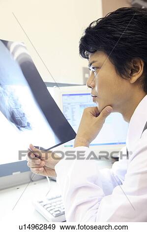Doctor looking at X-ray View Large Photo Image Stock Photo - Doctor looking at X-ray. Fotosearch