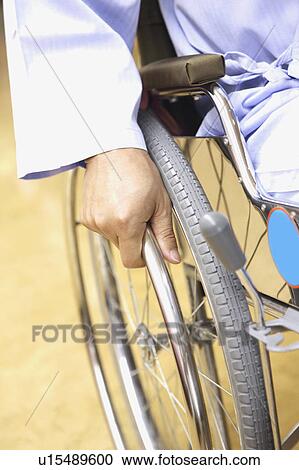 Stock Image - Hand rowing a wheelchair. Fotosearch