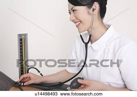 Stock Image - Nurse measuring blood pressure. Fotosearch
