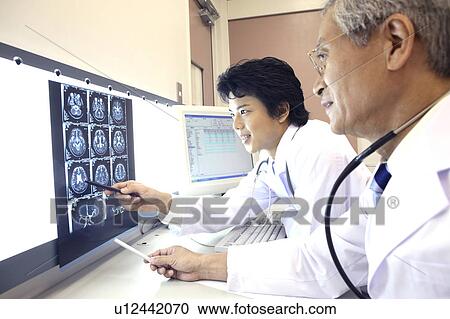 Doctor looking at X-ray View Large Photo Image Stock Image - Doctor looking at X-ray. Fotosearch