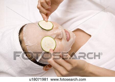 Stock Image - Woman applying a pack to her face. Fotosearch