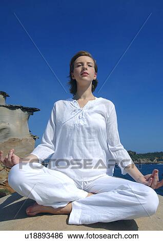 Low angle view of a young woman practicing yoga View Large Photo Image Stock Photograph - Low angle view of a young woman practicing yoga. Fotosearch