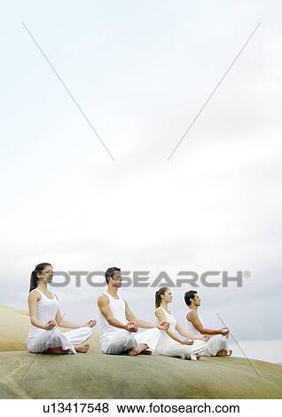 Stock Photo - Low angle view of two young men and two young women practicing yoga. Fotosearch