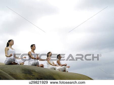 Stock Photo - Low angle view of two young men and two young women practicing yoga. Fotosearch