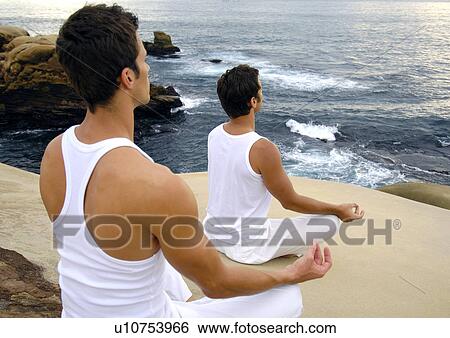 Stock Photograph - Rear view of two young men practicing yoga. Fotosearch