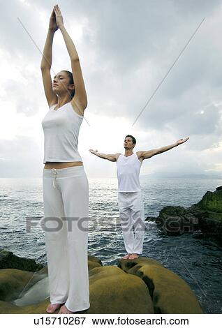 Stock Photo - Young woman and a young man practicing yoga. Fotosearch
