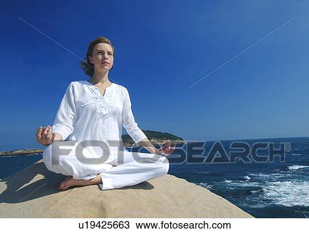 Stock Image - Young woman practicing yoga. Fotosearch
