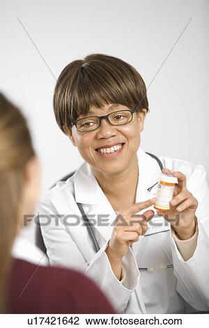 African American middle-aged female doctor sitting at desk explaining medication to Caucasian mid-adult female patient. View Large Photo Image Stock Image - African American middle-aged female doctor sitting at desk explaining medication to Caucasian mid-adult female patient.. Fotosearch