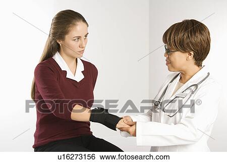 African American middle-aged female doctor examining wrist of Caucasian mid-adult female patient. View Large Photo Image Stock Photograph - African American middle-aged female doctor examining wrist of Caucasian mid-adult female patient.. Fotosearch