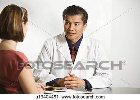 Asian American male doctor consulting with Caucasian female patient. View Large Photo Image Stock Image - Asian American male doctor consulting with Caucasian female patient.. Fotosearch