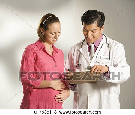 Asian American male doctor consulting with pregnant Caucasian woman. View Large Photo Image Stock Photo - Asian American male doctor consulting with pregnant Caucasian woman.. Fotosearch