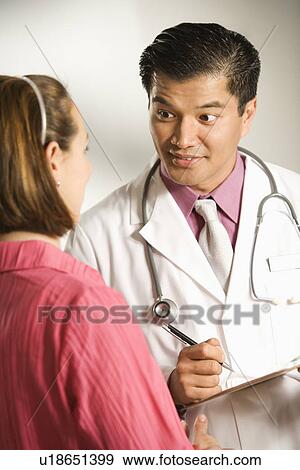 Asian American male doctor consulting with Caucasian woman. View Large Photo Image Stock Photo - Asian American male doctor consulting with Caucasian woman.. Fotosearch