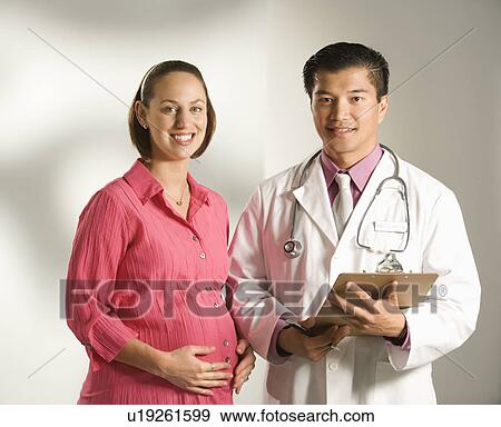 Asian American male doctor consulting with pregnant Caucasian woman. View Large Photo Image Stock Photo - Asian American male doctor consulting with pregnant Caucasian woman.. Fotosearch