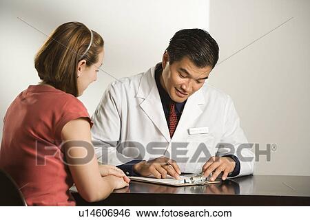 Asian American male doctor consulting with Caucasian female patient. View Large Photo Image Stock Photograph - Asian American male doctor consulting with Caucasian female patient.. Fotosearch
