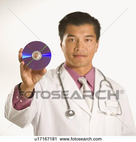 Stock Image - Asian American male doctor holding out compact disc.. Fotosearch