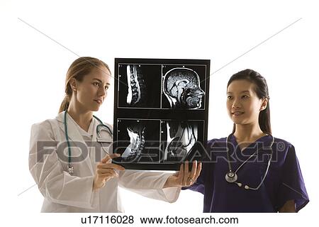 Caucasian and Asian Chinese mid-adult female doctors analyzing x-ray. View Large Photo Image Stock Photo - Caucasian and Asian Chinese mid-adult female doctors analyzing x-ray. . Fotosearch