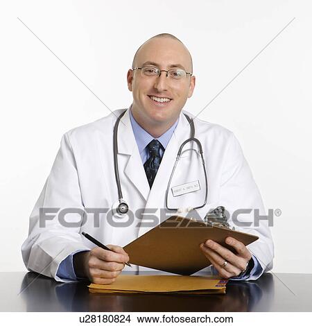 Picture - Caucasian mid adult male physician sitting at desk smiling.. Fotosearch