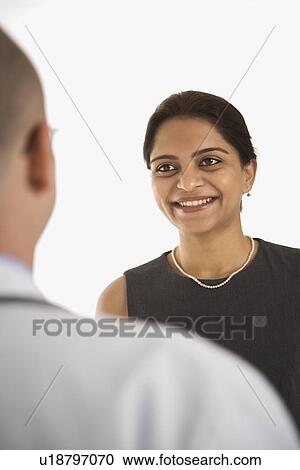 Stock Image - Caucasian mid adult male physician talking with Indian woman patient.. Fotosearch