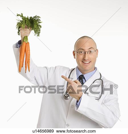 Caucasian mid adult male physician holding and pointing to bunch of carrots. View Large Photo Image Stock Photo - Caucasian mid adult male physician holding and pointing to bunch of carrots.. Fotosearch