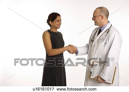 Stock Photo - Caucasian mid adult male physician talking with Indian woman patient.. Fotosearch