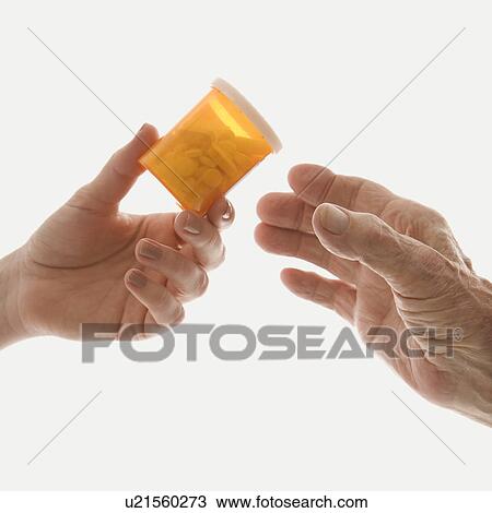 Close-up of mid-adult Caucasian female's hand handing medication bottle to elderly Caucasian male hand. View Large Photo Image Stock Image - Close-up of mid-adult Caucasian female's hand handing medication bottle to elderly Caucasian male hand.. Fotosearch