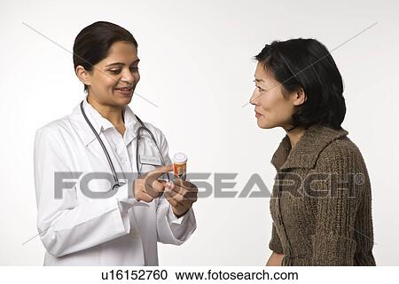 Indian woman doctor explaining medication to Asian woman patient. View Large Photo Image Stock Image - Indian woman doctor explaining medication to Asian woman patient.. Fotosearch