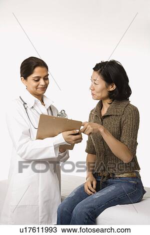 Stock Image - Indian woman doctor with Asian woman patient.. Fotosearch