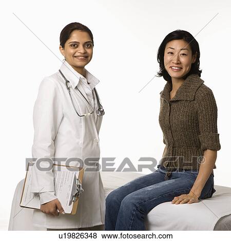 Stock Photo - Indian woman doctor with Asian woman patient.. Fotosearch