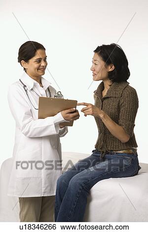 Stock Photograph - Indian woman doctor with Asian woman patient.. Fotosearch