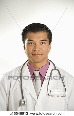 Stock Image - Portrait of Asian American male doctor against white background.. Fotosearch