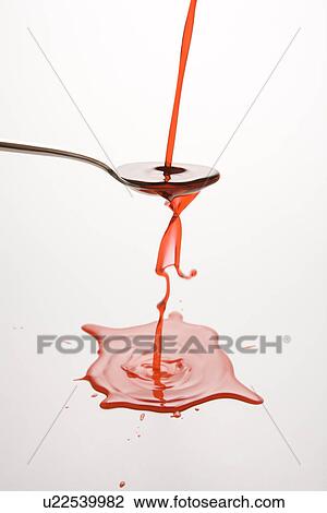 Stock Image - Stream of red cough syrup overflowing spoon into puddle below.. Fotosearch